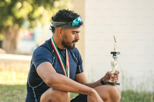 a man sitting on the ground holding a trophy