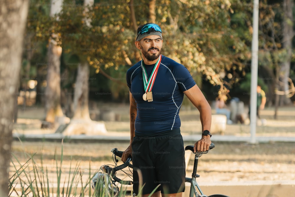 Un hombre con una medalla de pie junto a una bicicleta