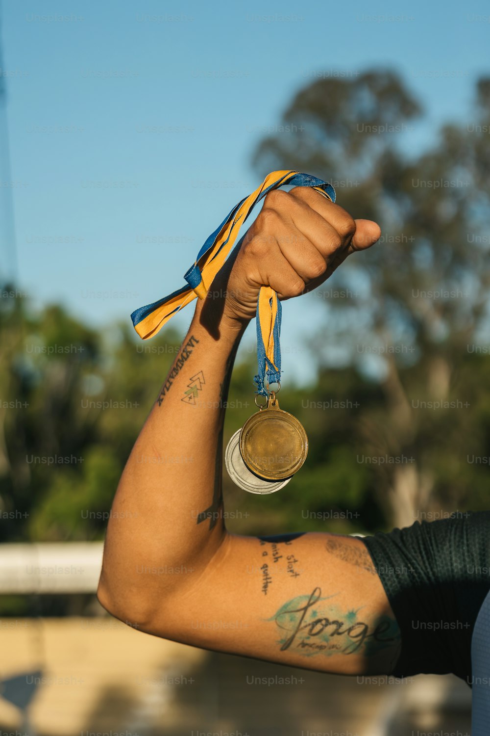a man with a tattoo on his arm holding a medal