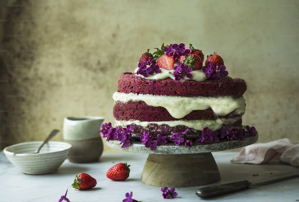 a cake sitting on top of a table covered in purple flowers