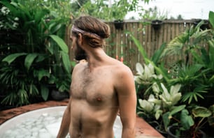 a man with no shirt standing in front of a hot tub