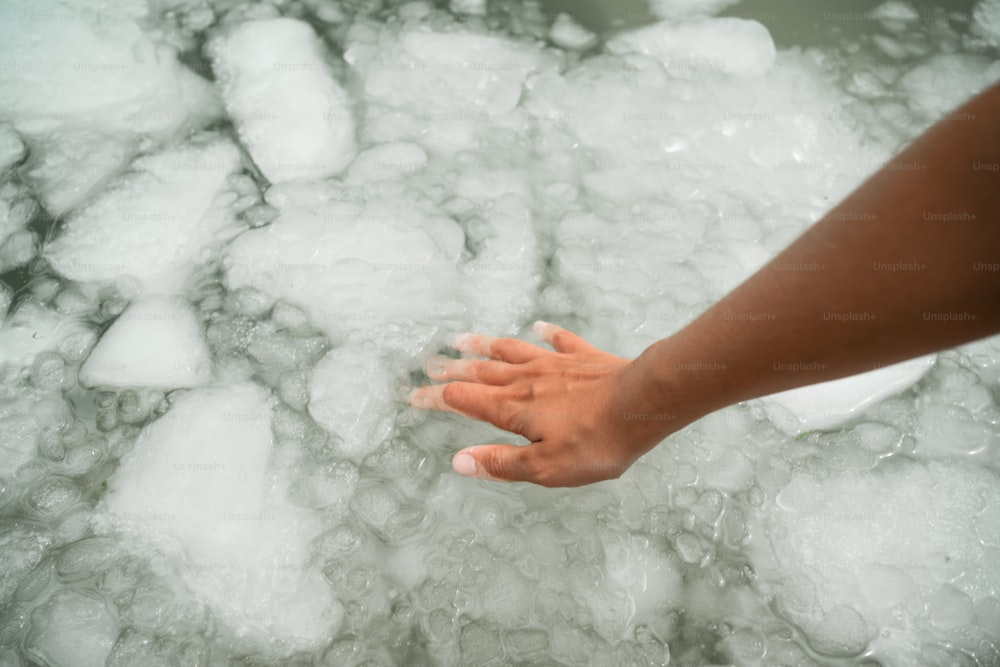 a person reaching for something in a pool of ice