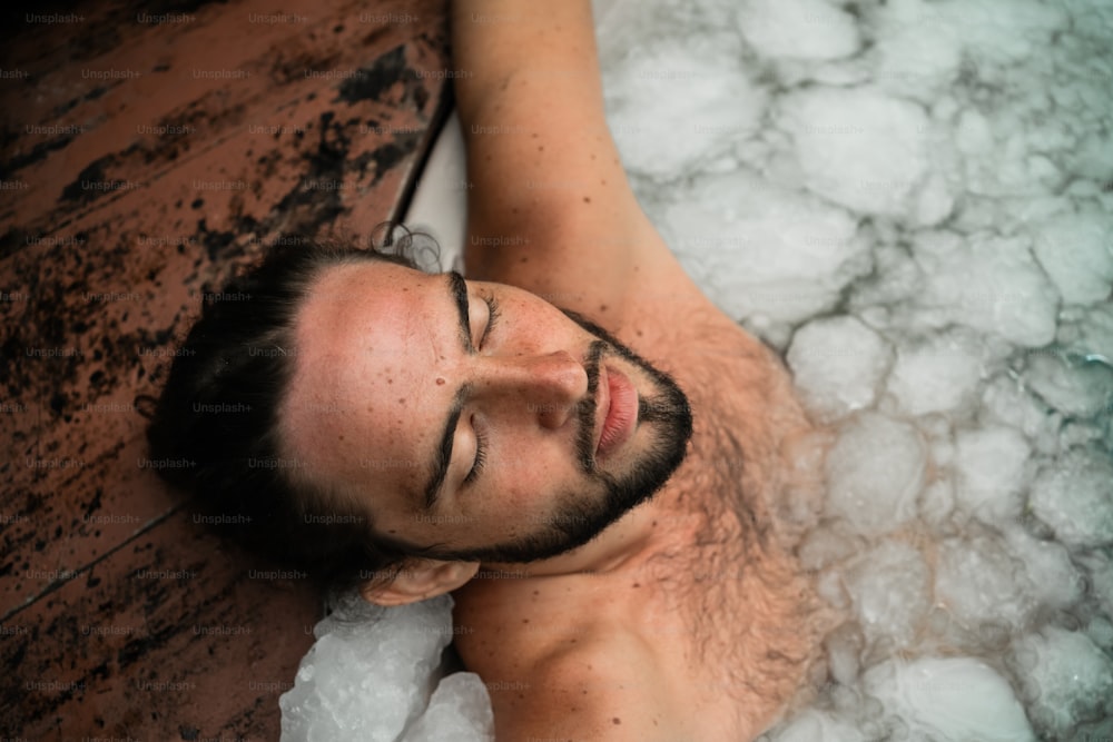 a man laying in a hot tub with bubbles around him