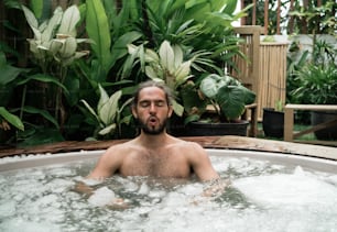 a man in a hot tub surrounded by plants