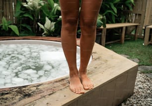 a person standing on a ledge next to a hot tub