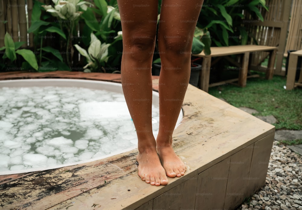 a person standing on a ledge next to a hot tub