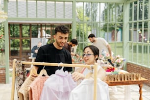 a man and a woman looking at dresses on a rack