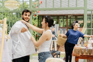 a man helping a woman put on a white shirt