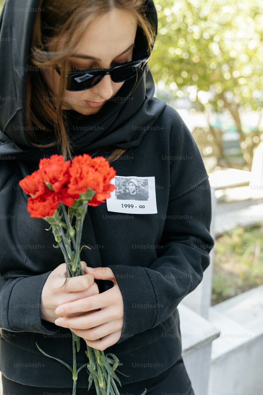 a woman in a hoodie holding a bunch of flowers