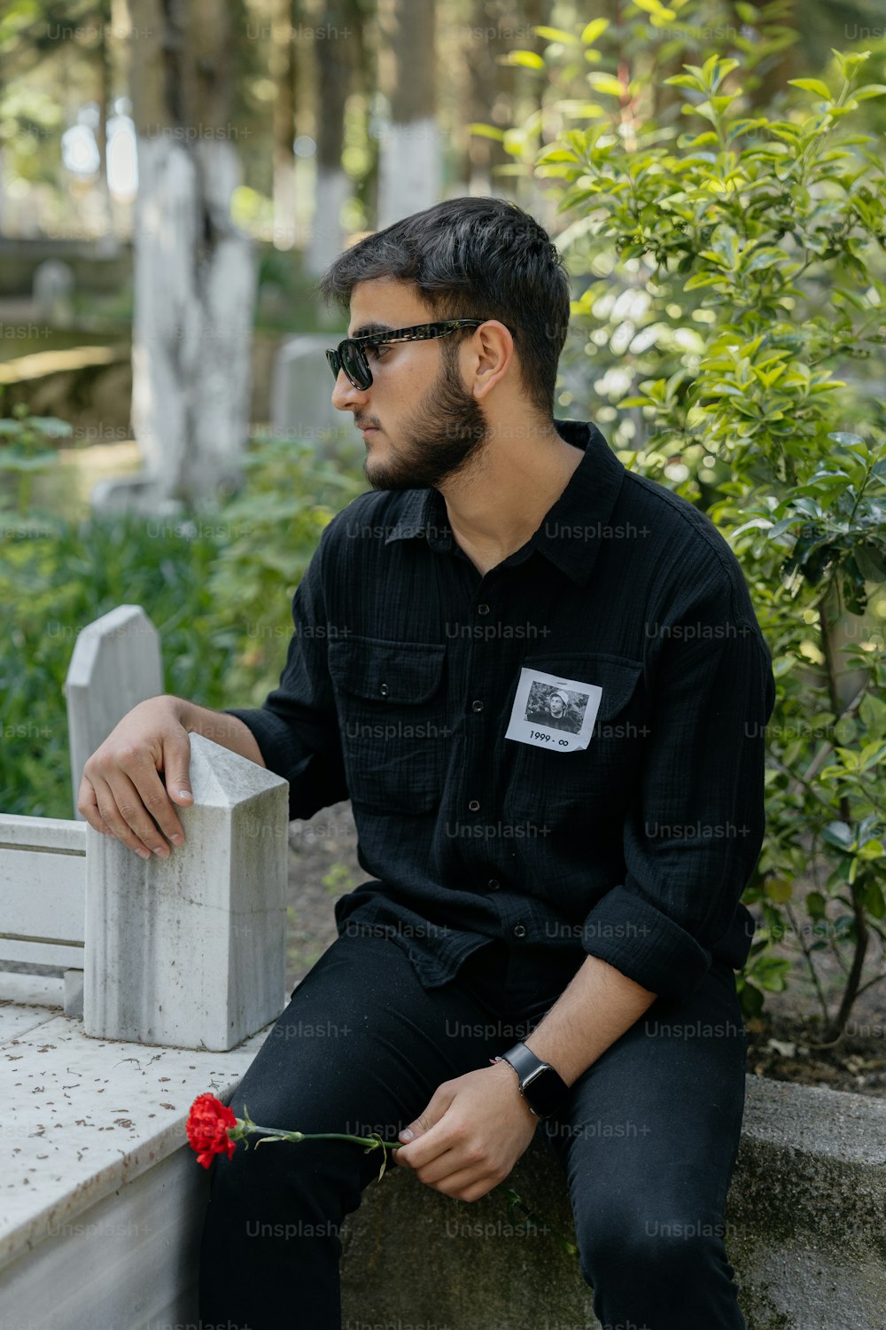 un uomo seduto su una panchina di cemento con una rosa in mano