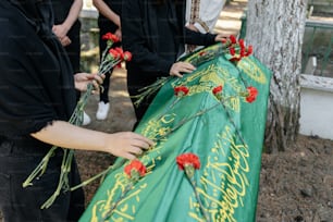 a group of people standing around a green cloth