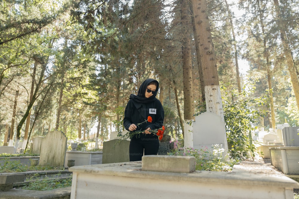 a woman in a black hoodie standing in a cemetery
