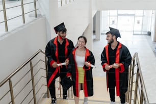 three graduates walking down a flight of stairs