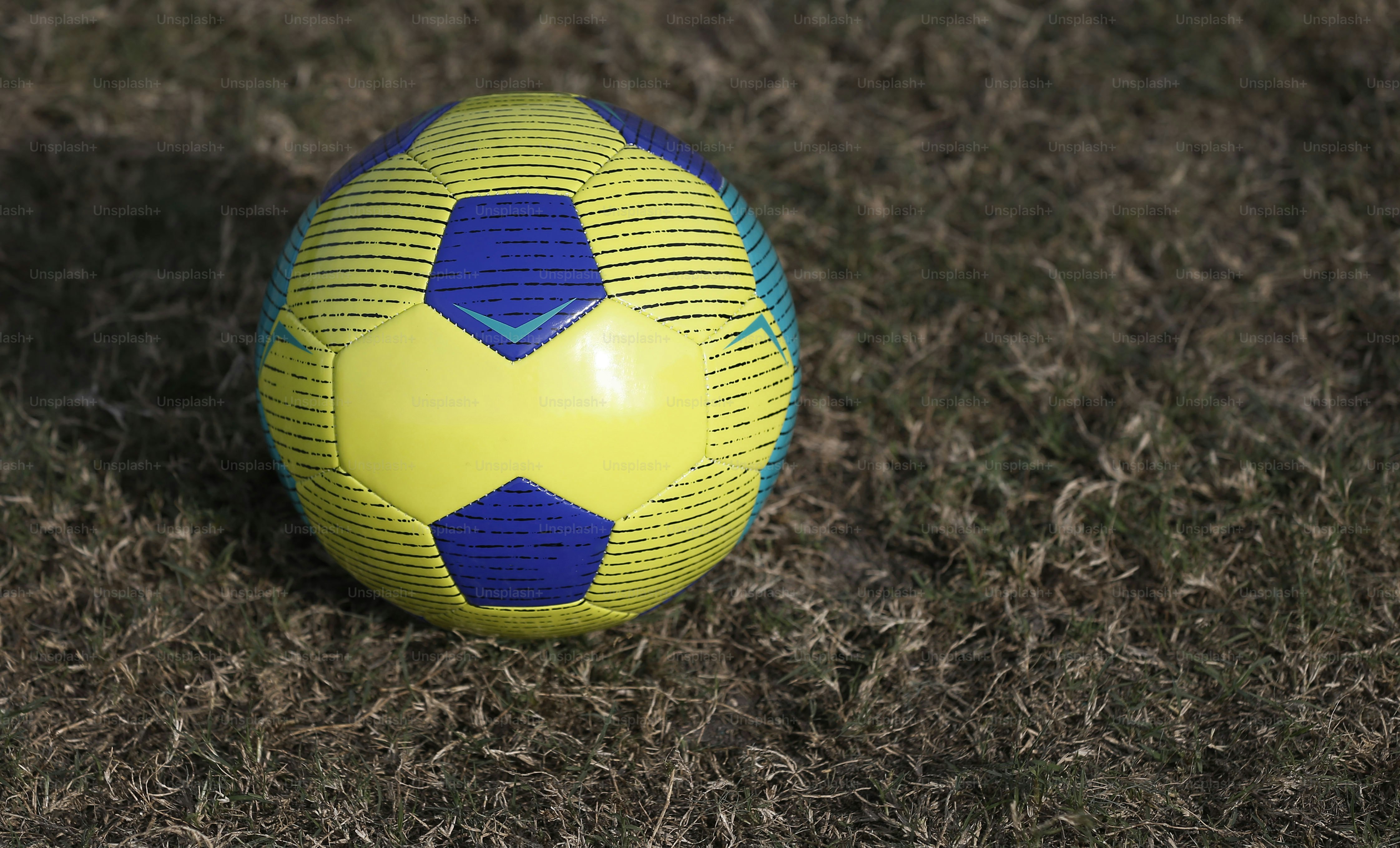 uma bola de futebol amarela e azul sentada na grama