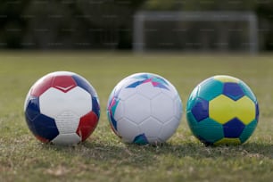 three soccer balls sitting on top of a field