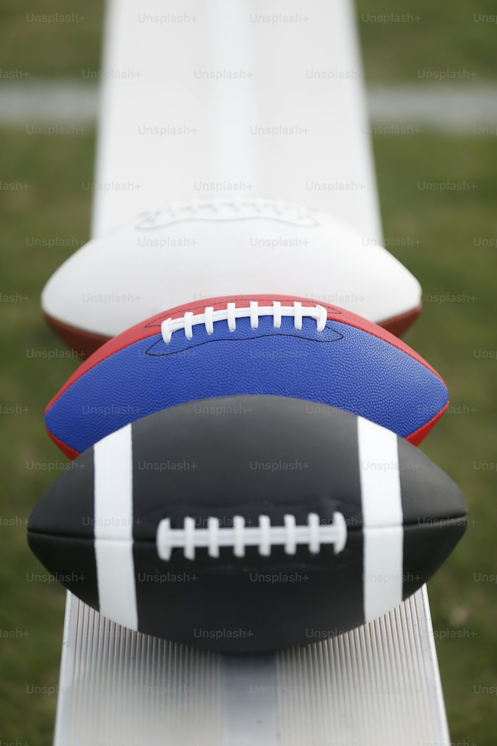 two footballs sitting on top of a white bench