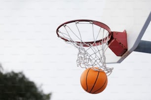 Un pallone da basket sta passando attraverso la rete di un canestro da basket