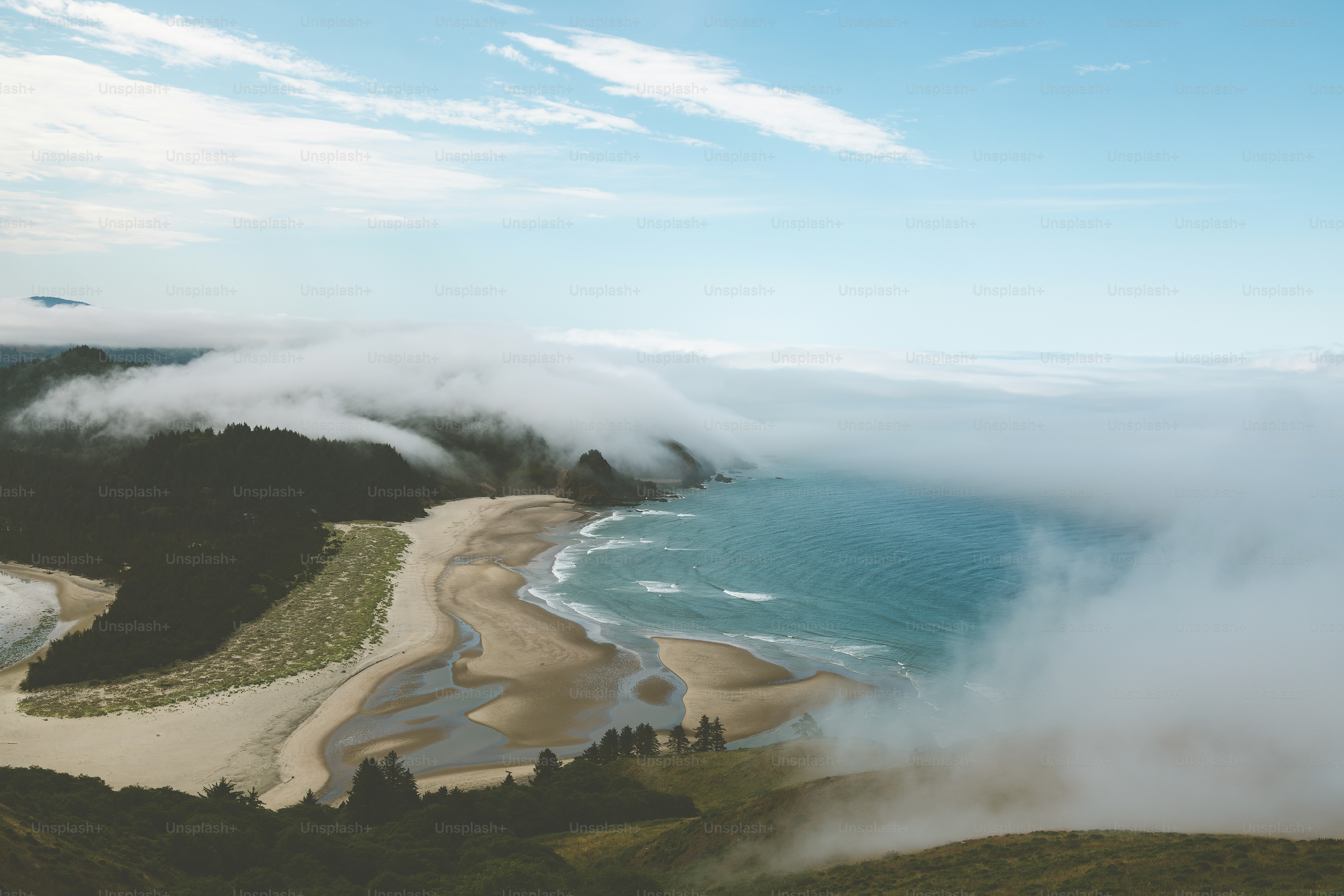 an aerial view of a beach surrounded by clouds