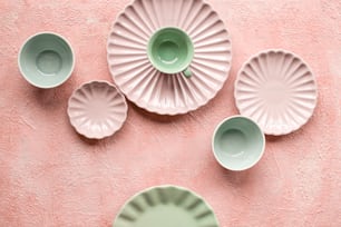 a pink wall with five green plates on it