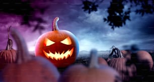 Un design di sfondo a tema Halloween spettrale per eventi e feste. Un campo nebbioso con zucche di notte. Foto composita.