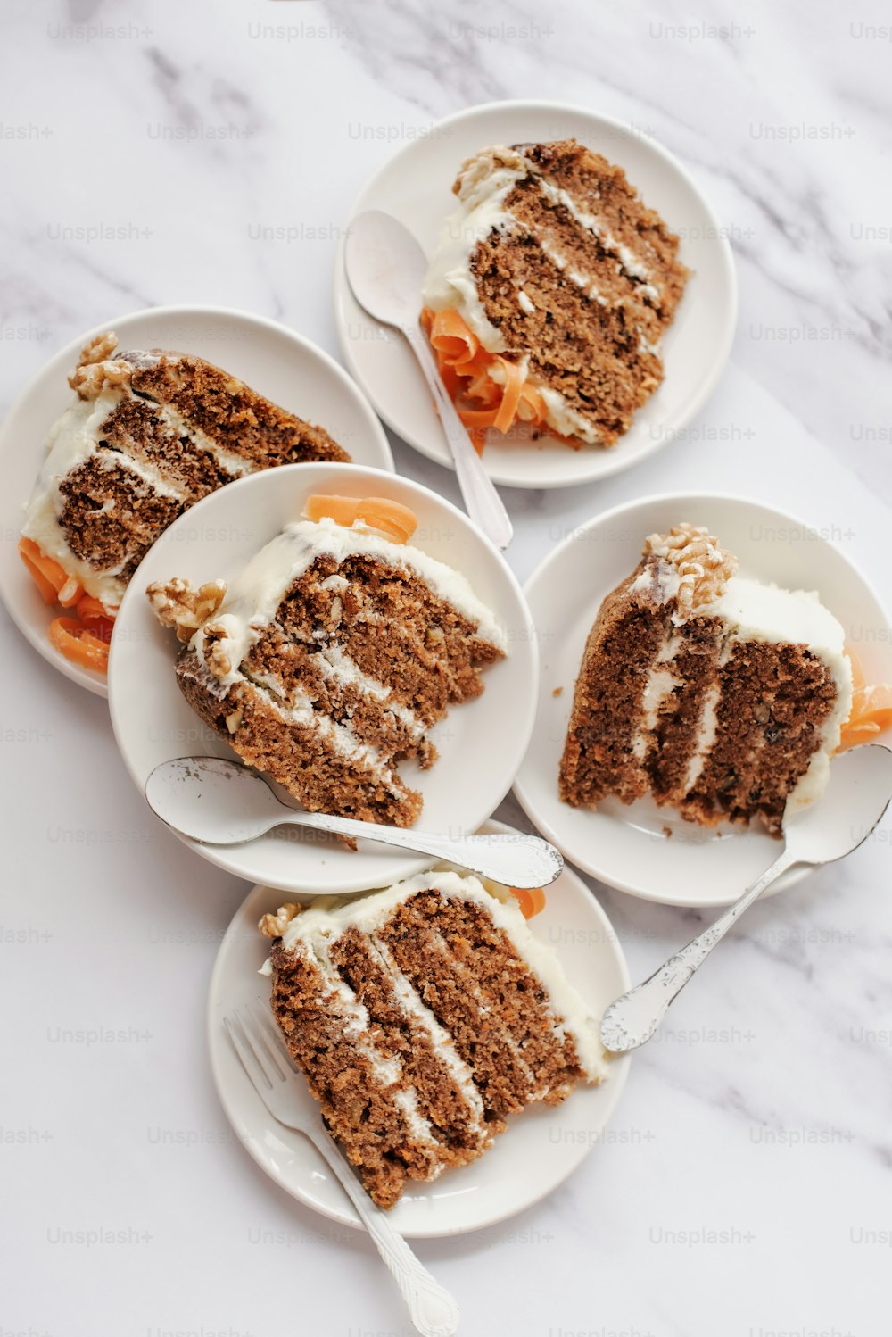 quatre assiettes avec des tranches de gâteau aux carottes dessus