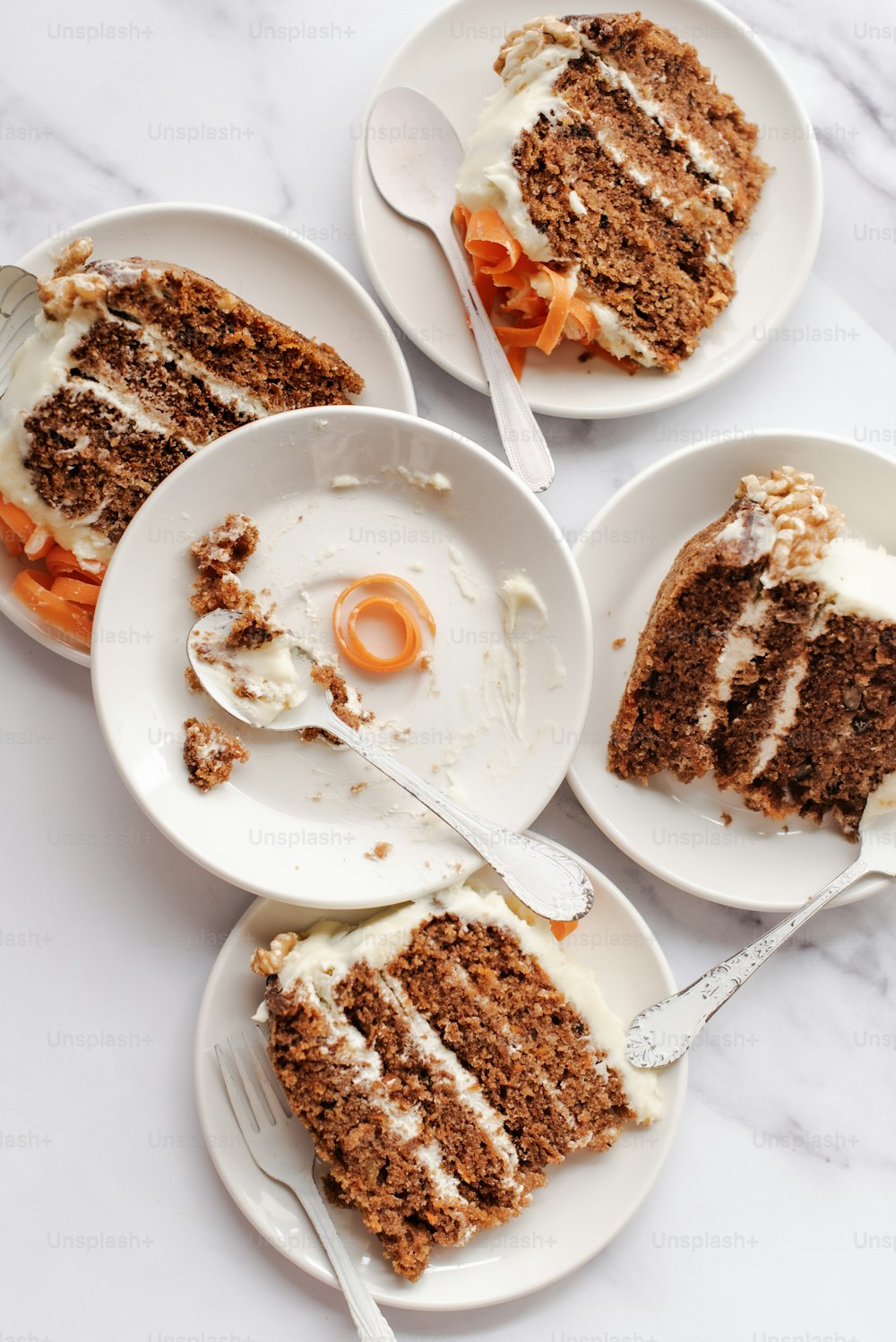 four plates of carrot cake with cream cheese frosting