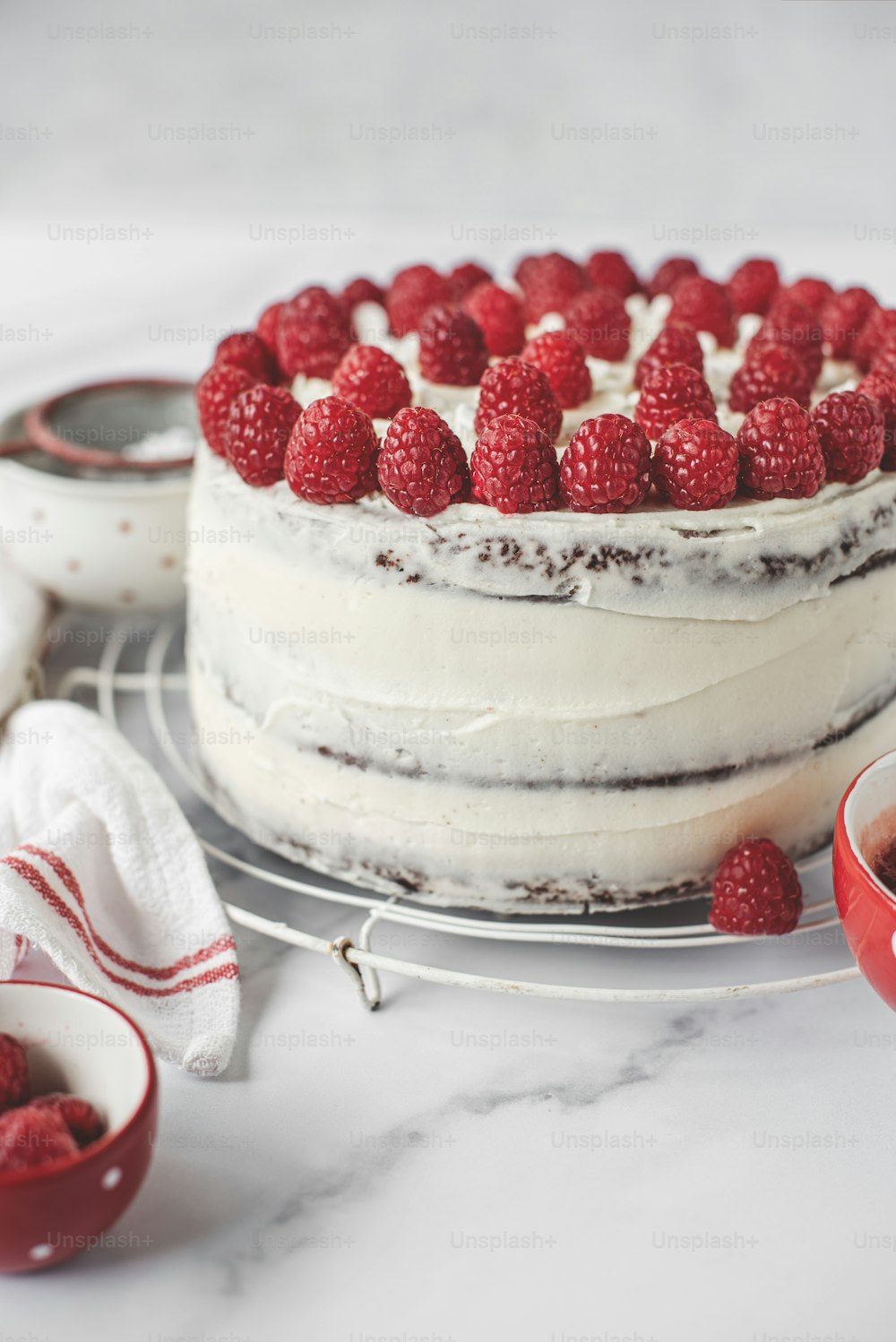 a cake with white frosting and raspberries on top