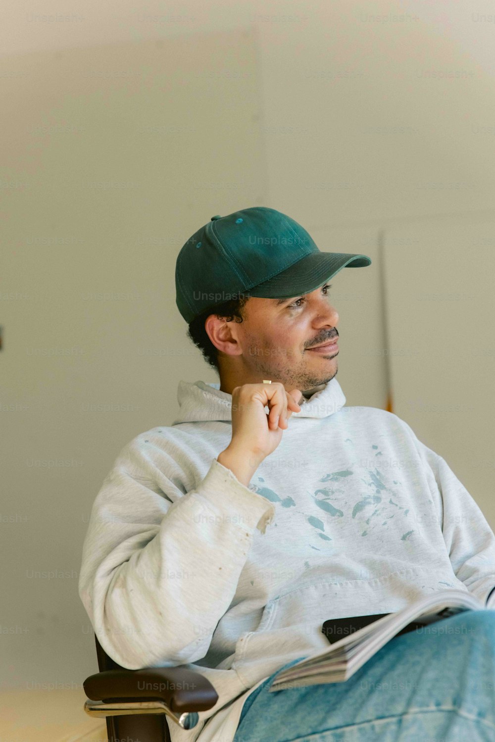 a man sitting in a chair wearing a green hat
