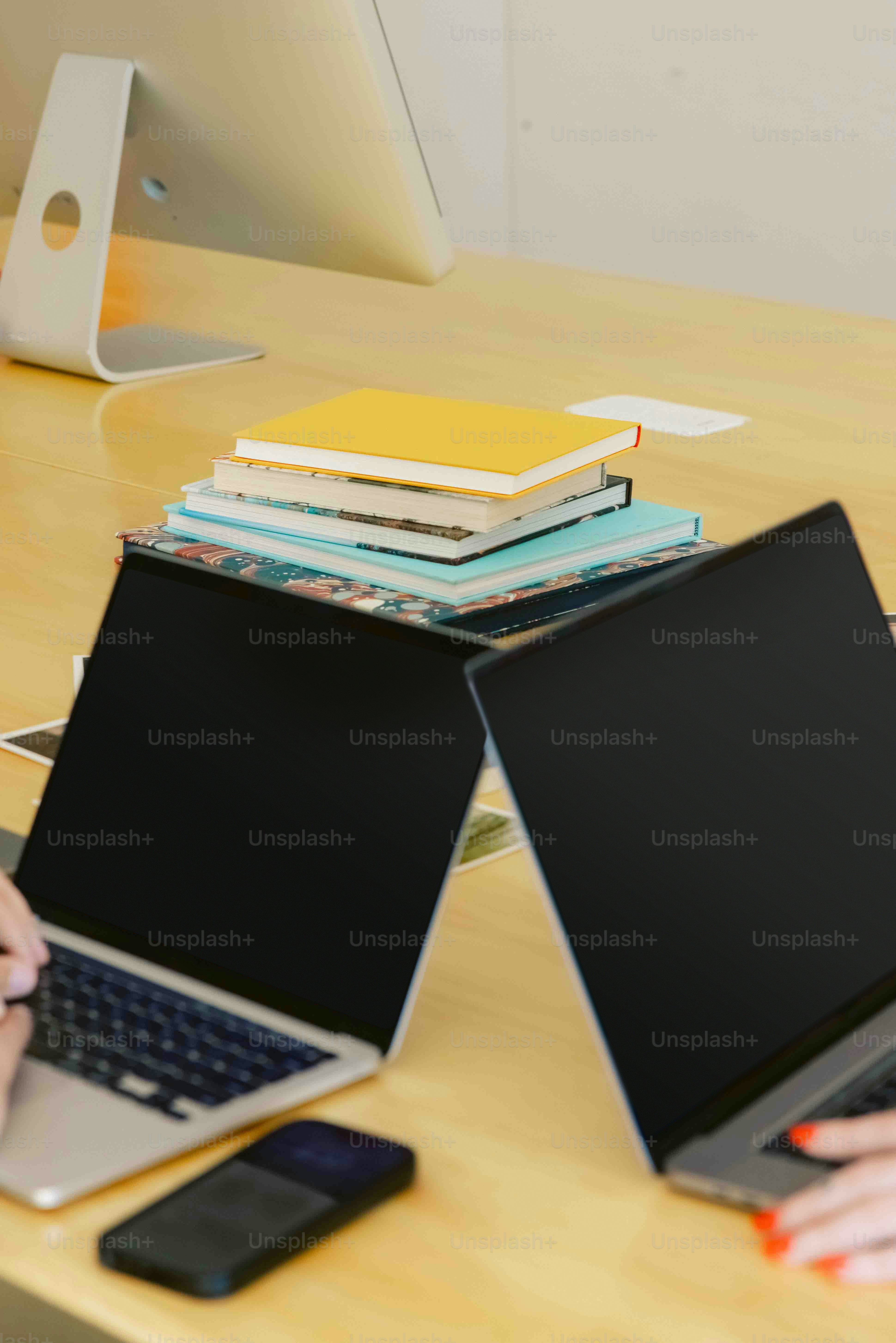 a woman sitting at a desk with two laptops