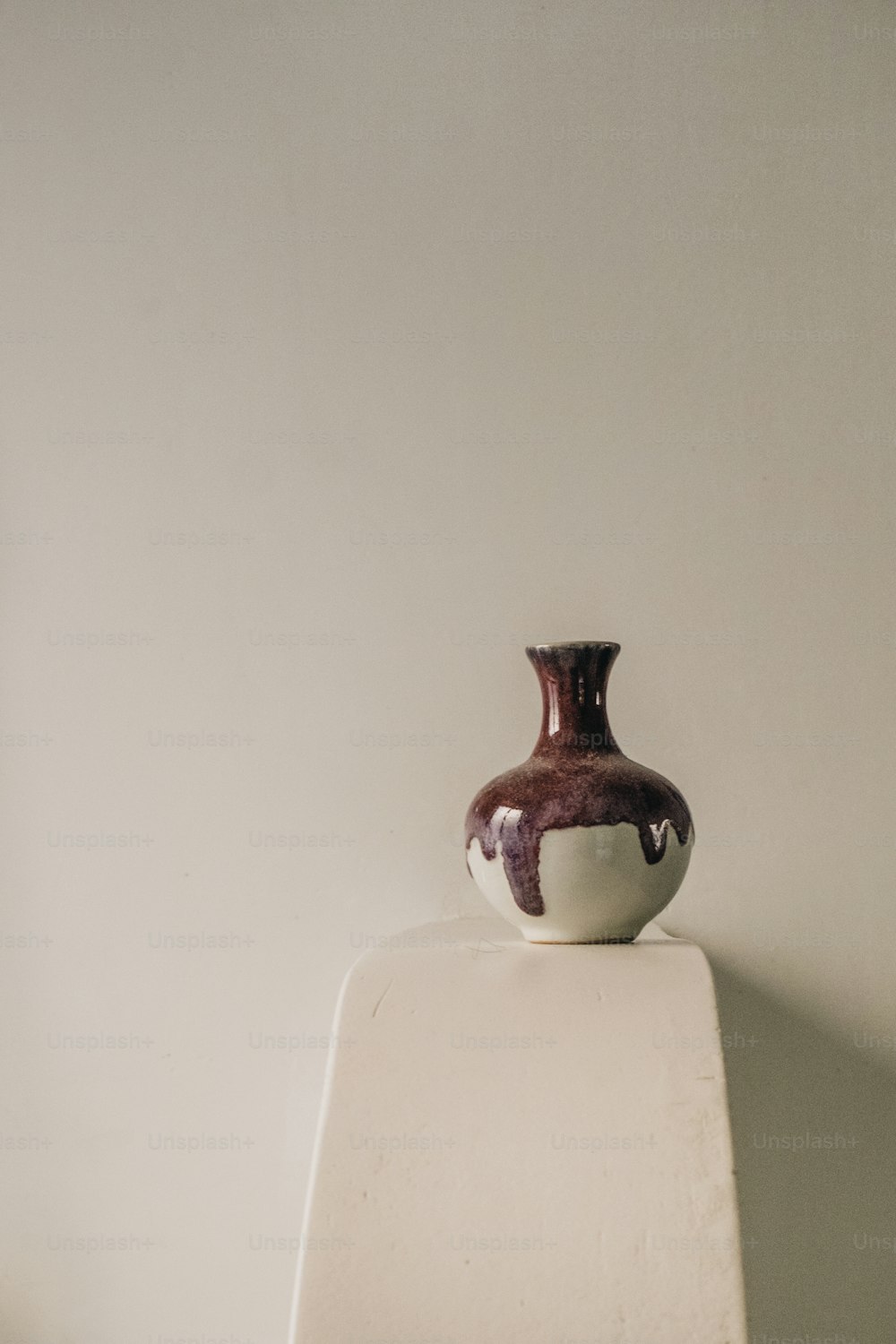 a brown and white vase sitting on top of a white shelf