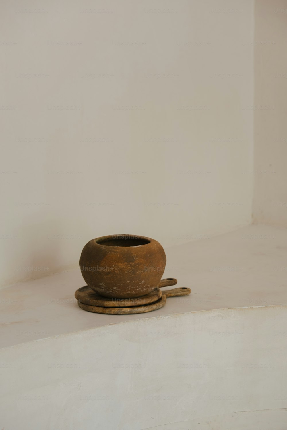 um vaso marrom sentado em cima de uma prateleira branca