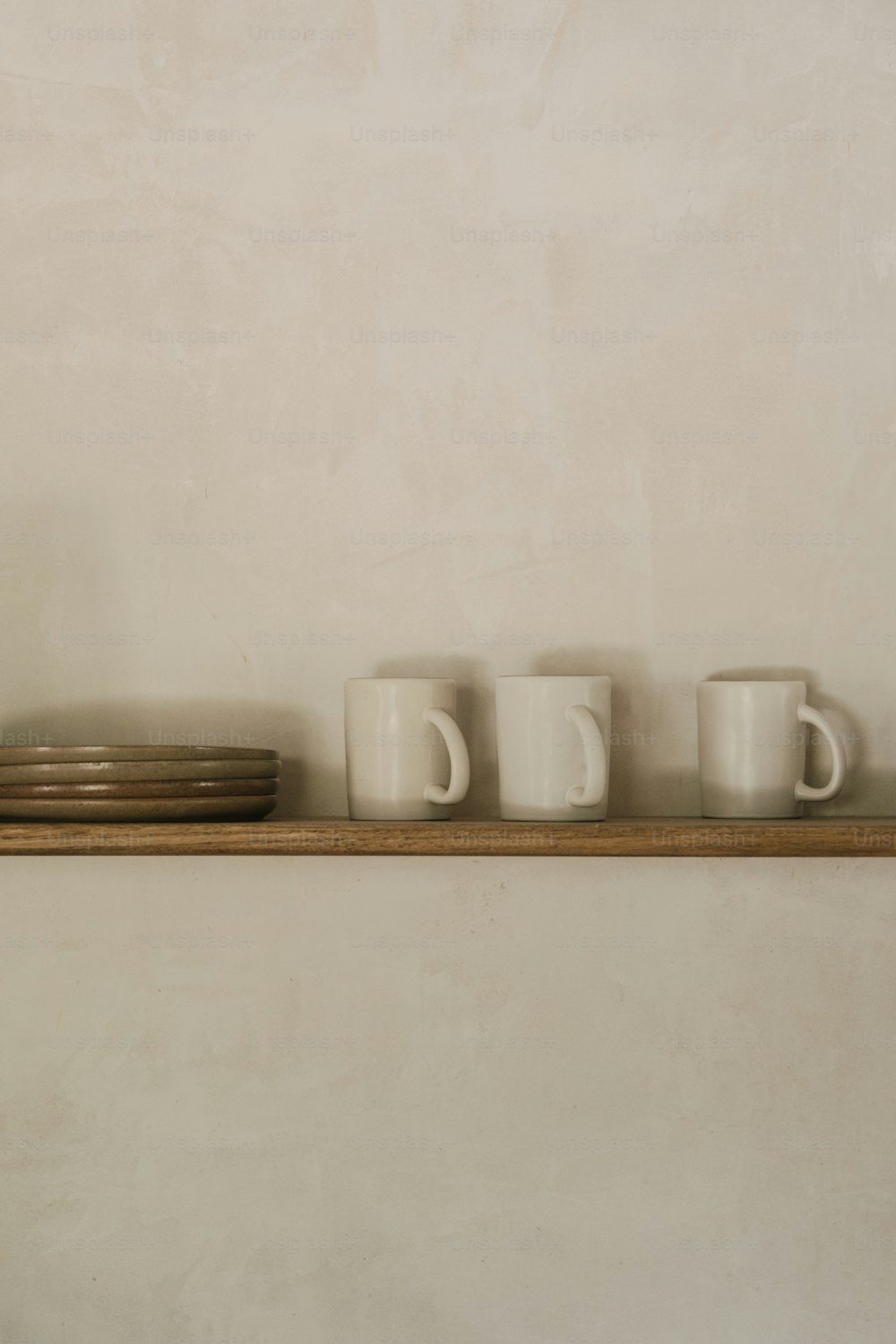 a shelf with three cups and a plate on it