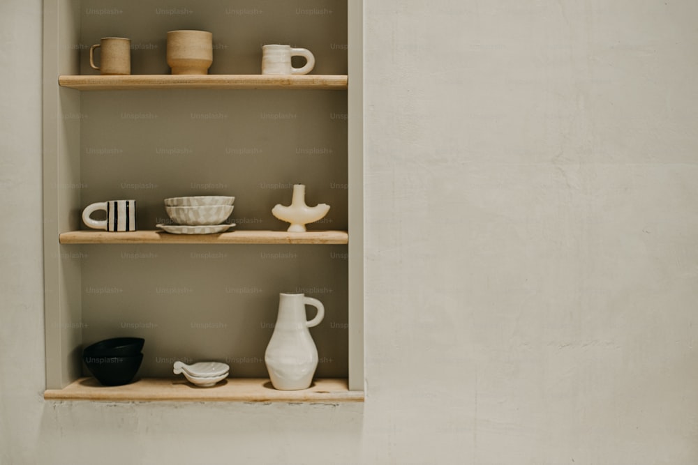 a shelf filled with cups and bowls on top of a wall