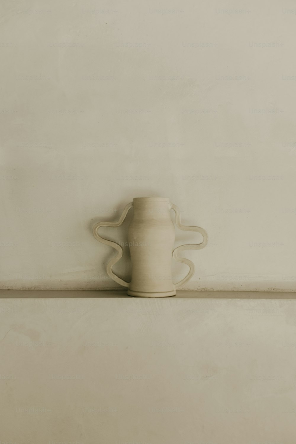 a white vase sitting on top of a shelf