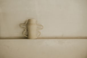 um vaso branco sentado em cima de uma prateleira
