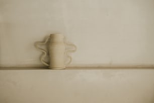 a white vase sitting on top of a shelf