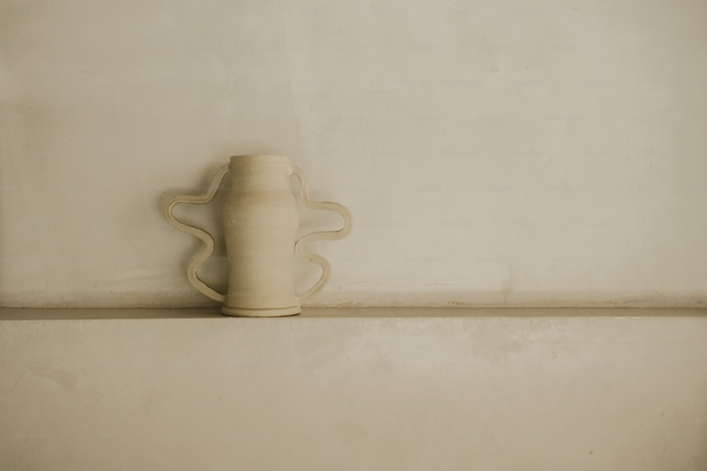 a white vase sitting on top of a shelf