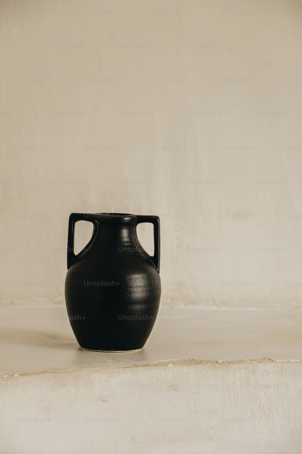 a black vase sitting on a white surface