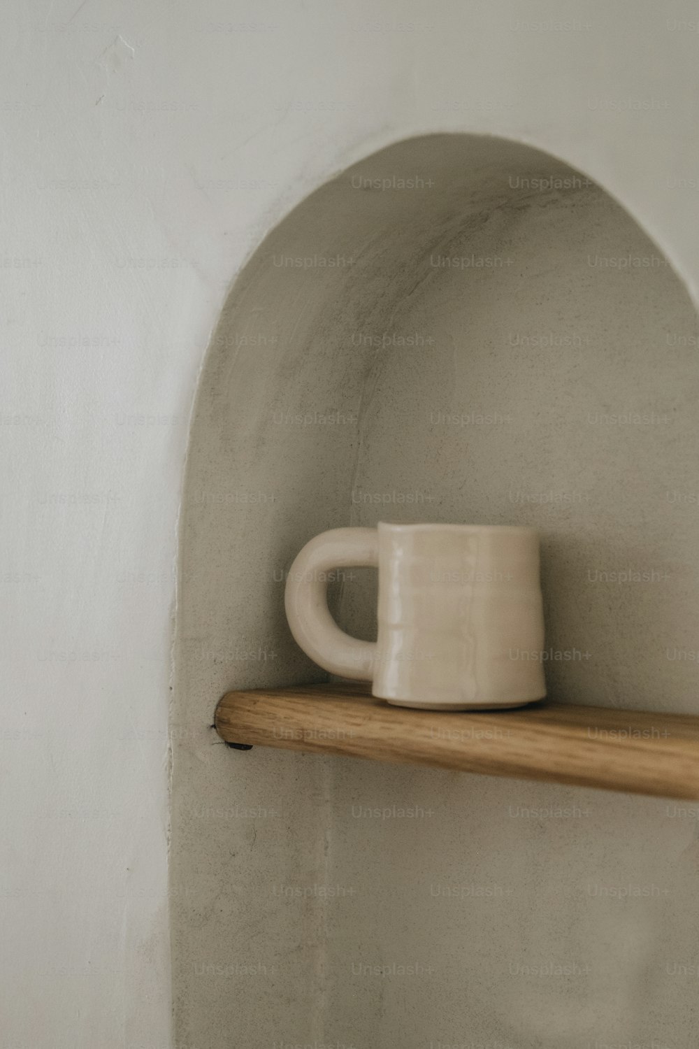 a white mug sitting on top of a wooden shelf