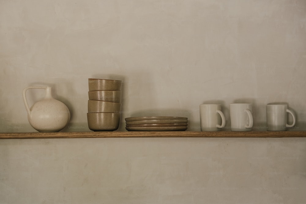a shelf that has some cups and a vase on it