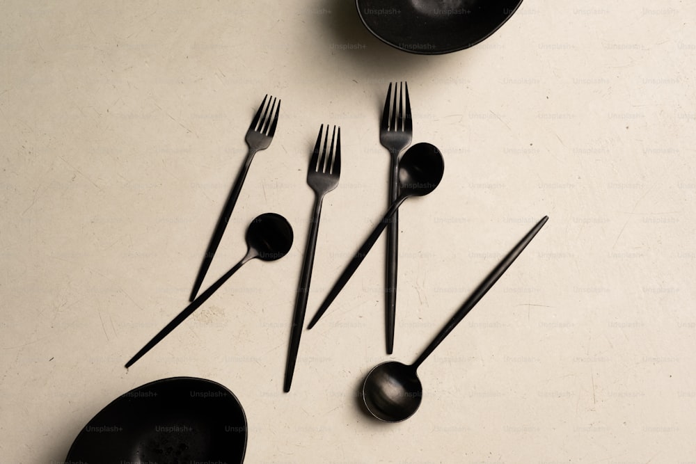 ein Tisch mit schwarzen Utensilien und schwarzen Tellern