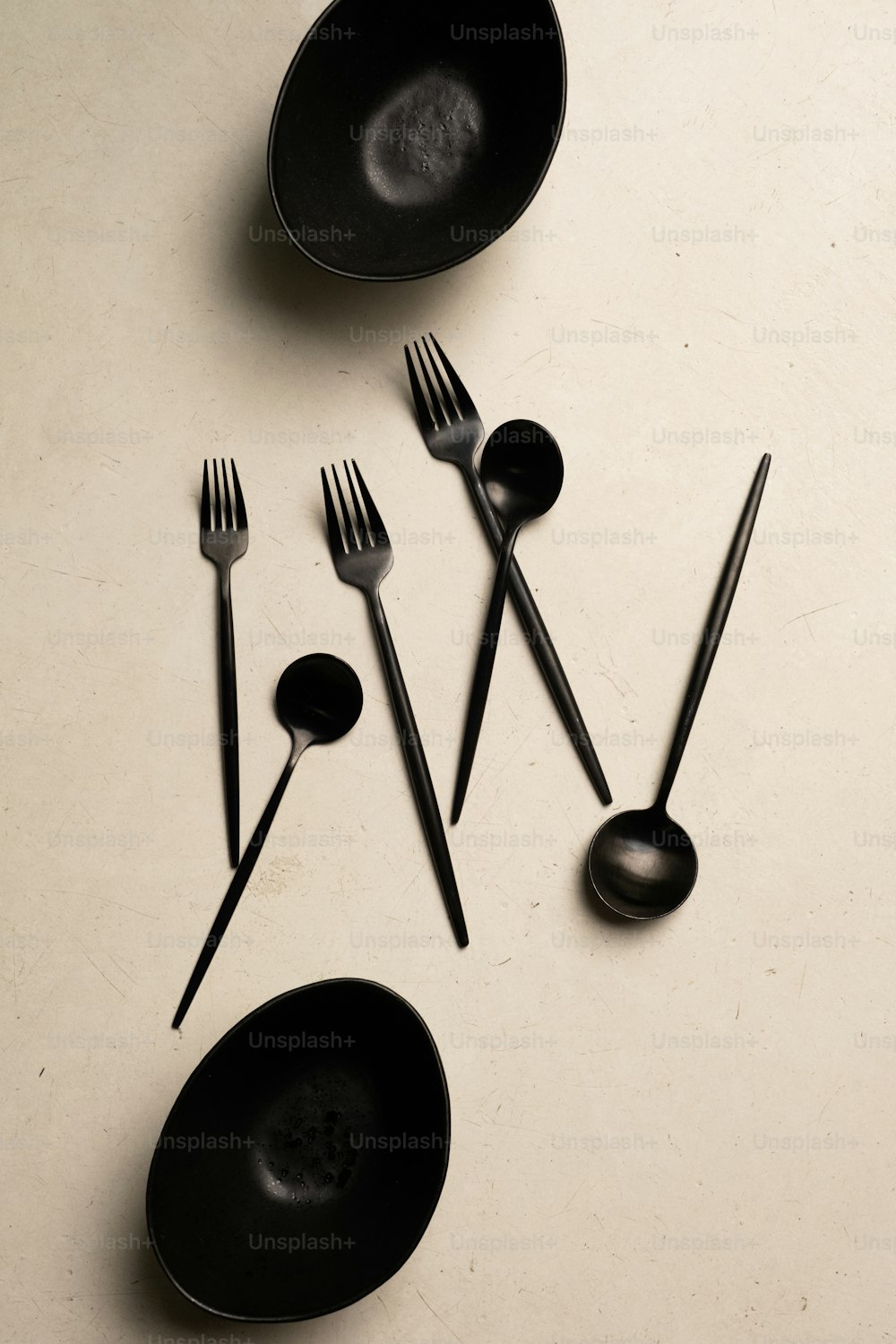 a table topped with black bowls and forks