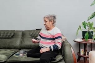 una mujer sentada en un sofá sosteniendo un control remoto