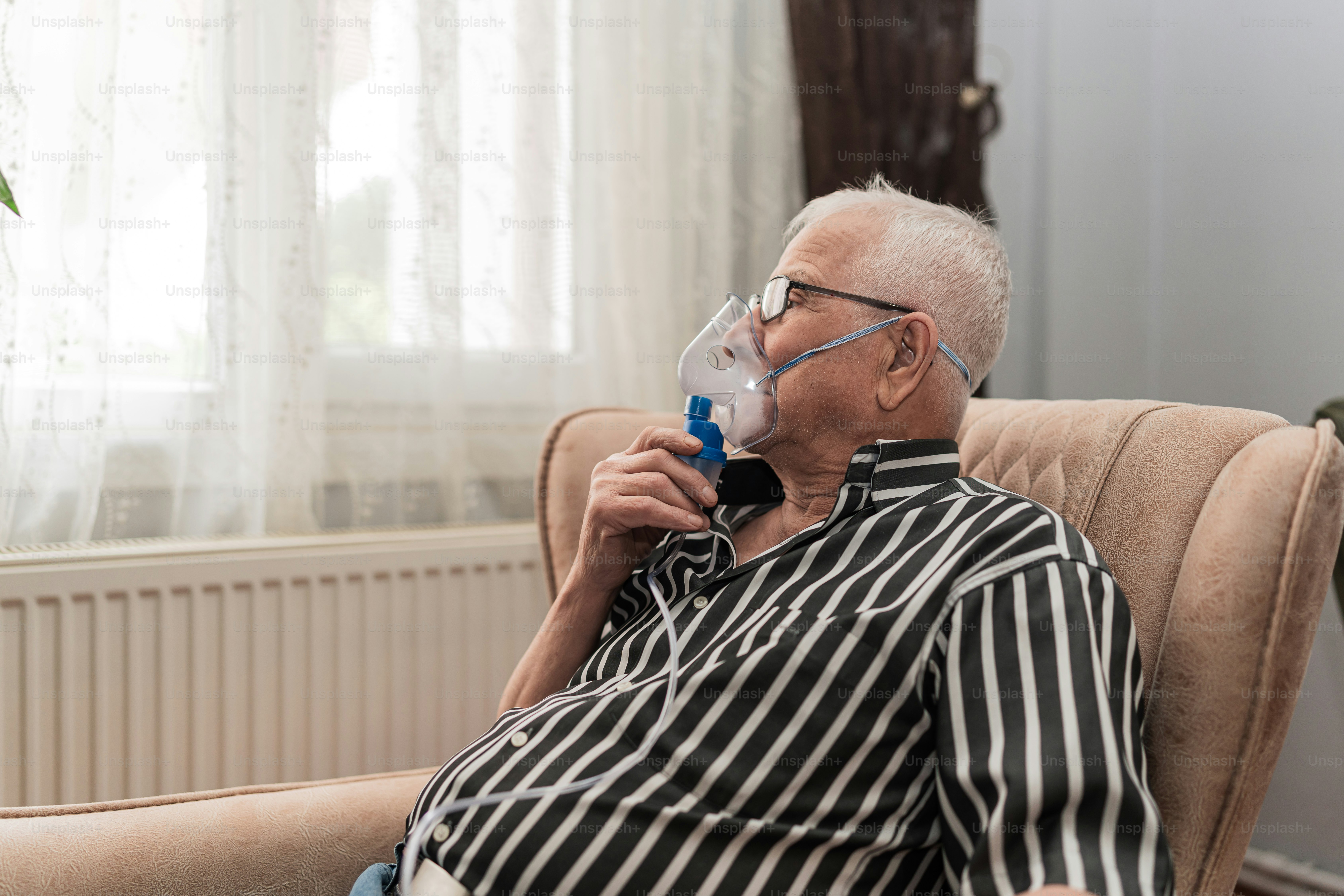 Un hombre sentado en una silla con una máscara en la cara