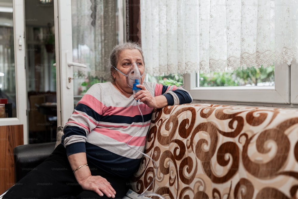 Un hombre sentado en un sofá con un dispositivo de respiración en la boca