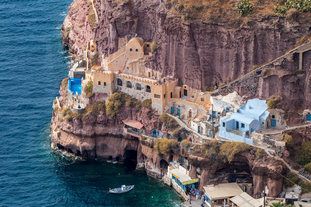 an aerial view of a cliff with a boat in the water