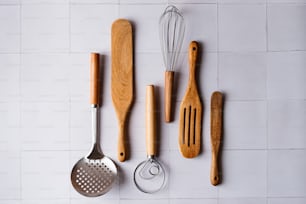 wooden utensils and wooden spatulas on a white tiled wall