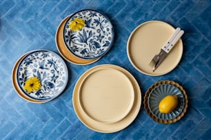 Ein Tisch mit Tellern und einer Zitrone neben Messer und Gabel