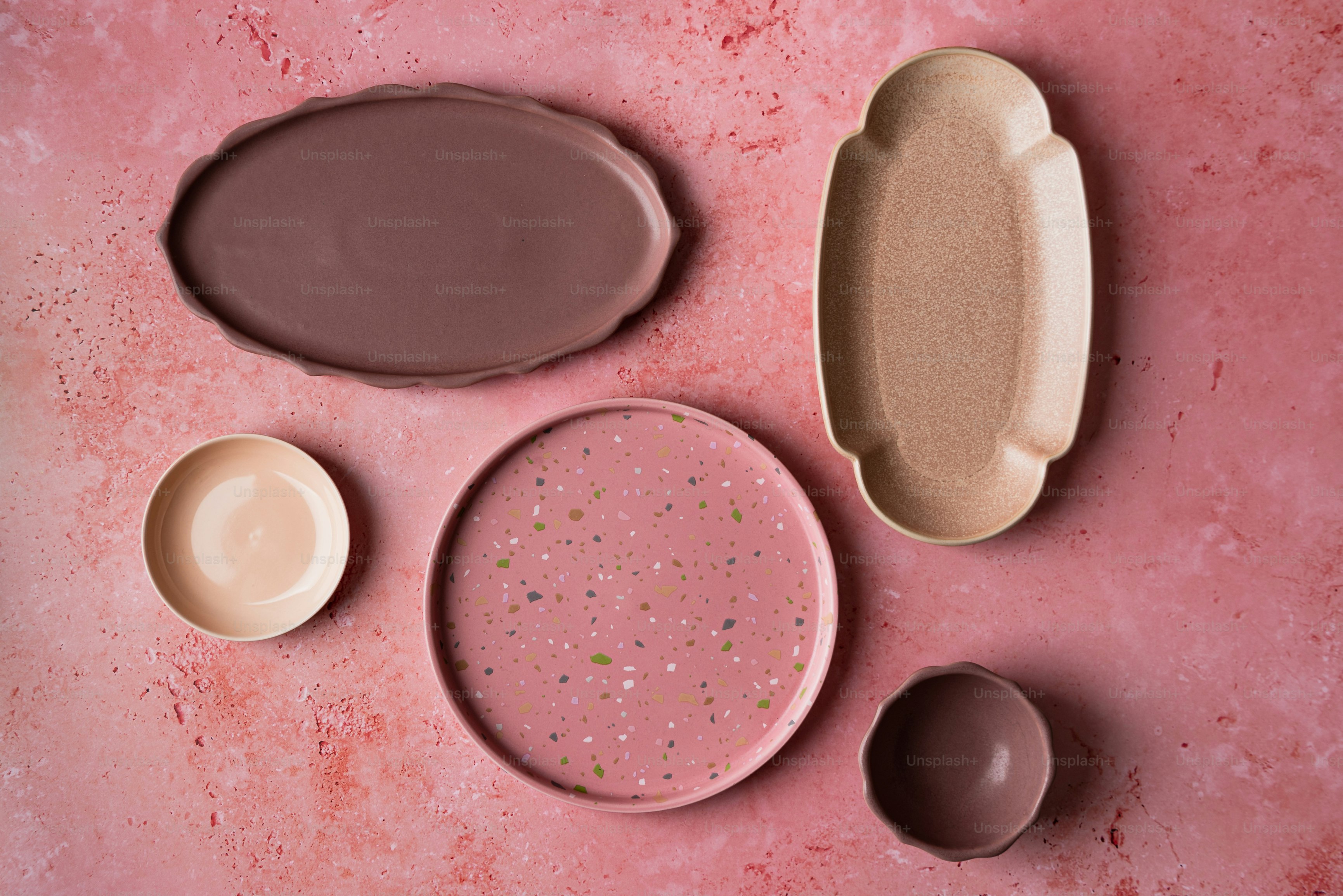 un tavolo sormontato da piatti e ciotole su una superficie rosa