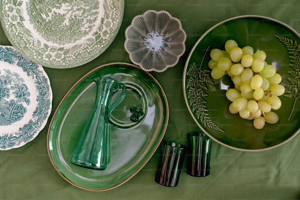 a table topped with plates and bowls filled with grapes